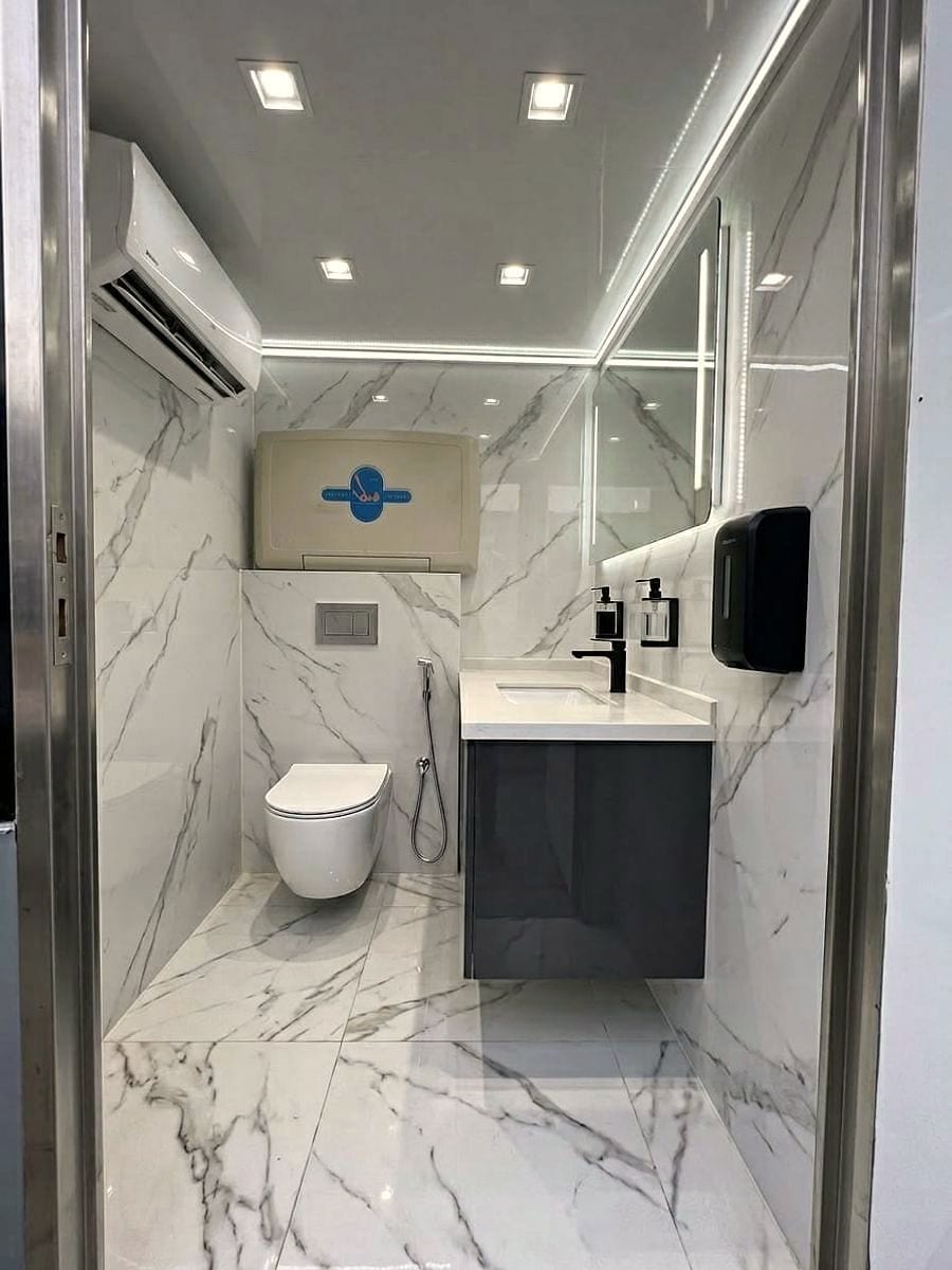 Cabine complète : climatiseur mural, miroir rétroéclairé, vasque et distributeur.